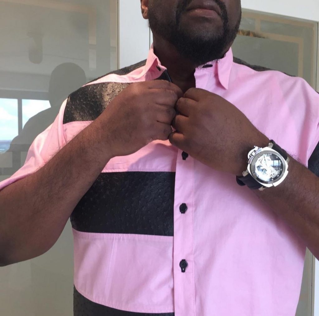 Man buttoning pink and black shirt